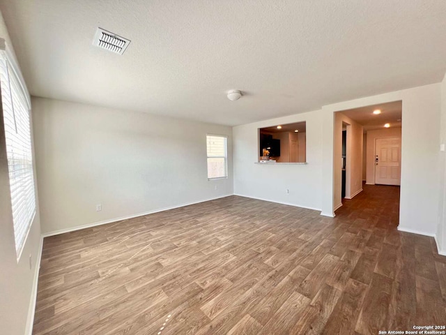 unfurnished living room featuring a textured ceiling and wood-type flooring