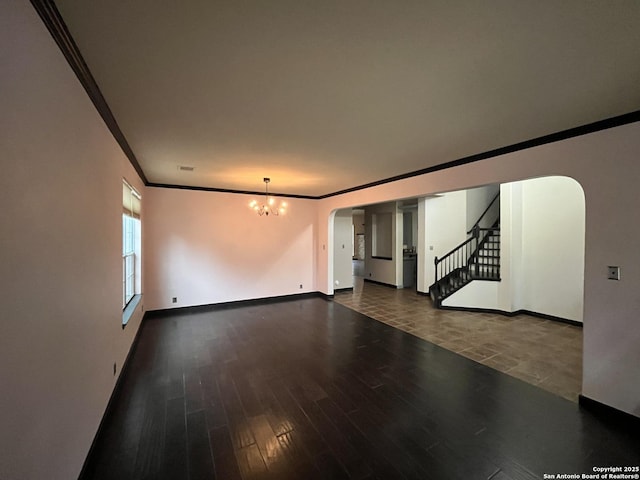 empty room featuring an inviting chandelier, ornamental molding, and dark hardwood / wood-style floors