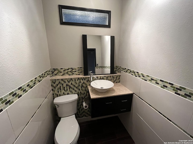 bathroom with tile walls, toilet, and vanity