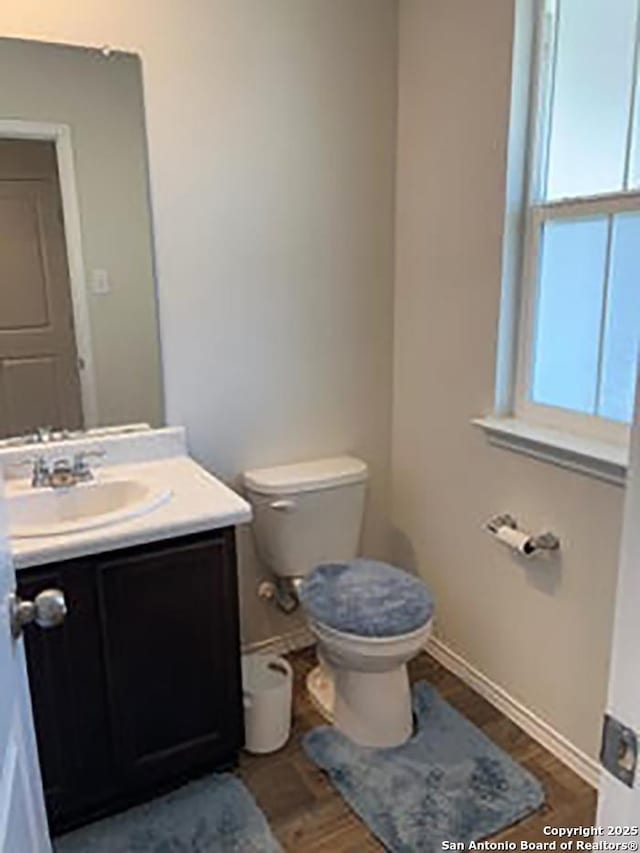 bathroom with toilet, hardwood / wood-style floors, and vanity