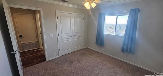 unfurnished bedroom featuring ceiling fan, crown molding, a closet, and carpet