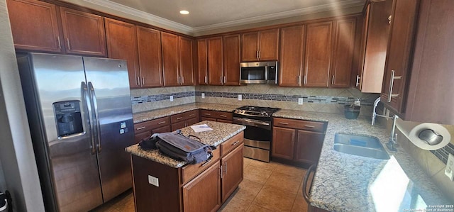 kitchen with appliances with stainless steel finishes, a center island, ornamental molding, light stone counters, and sink