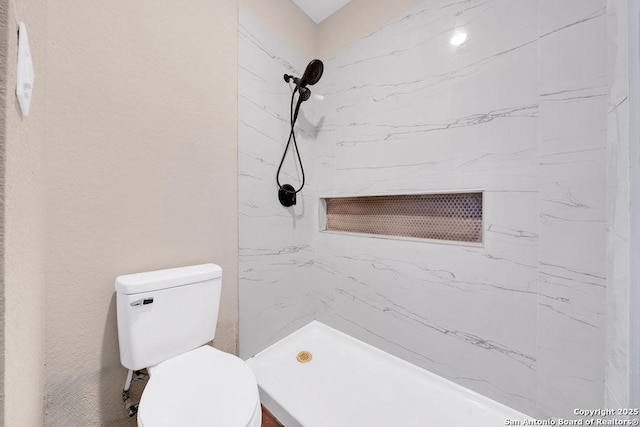 bathroom featuring toilet and tiled shower