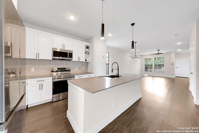 kitchen with decorative light fixtures, an island with sink, white cabinets, appliances with stainless steel finishes, and sink