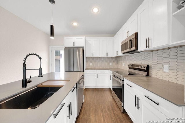 kitchen with pendant lighting, stainless steel appliances, decorative backsplash, white cabinetry, and sink