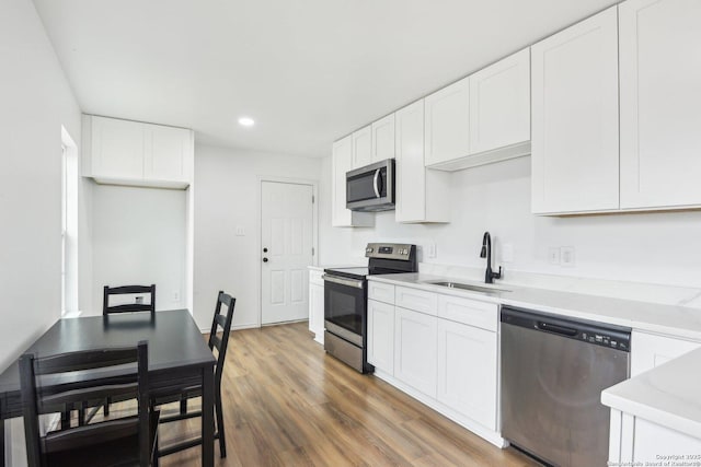 kitchen featuring stainless steel appliances, white cabinetry, dark hardwood / wood-style flooring, and sink