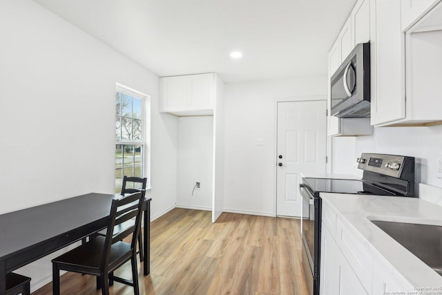 kitchen with sink, stainless steel appliances, white cabinets, and light hardwood / wood-style flooring