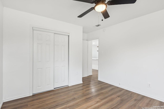 unfurnished bedroom with ceiling fan, dark hardwood / wood-style flooring, and a closet