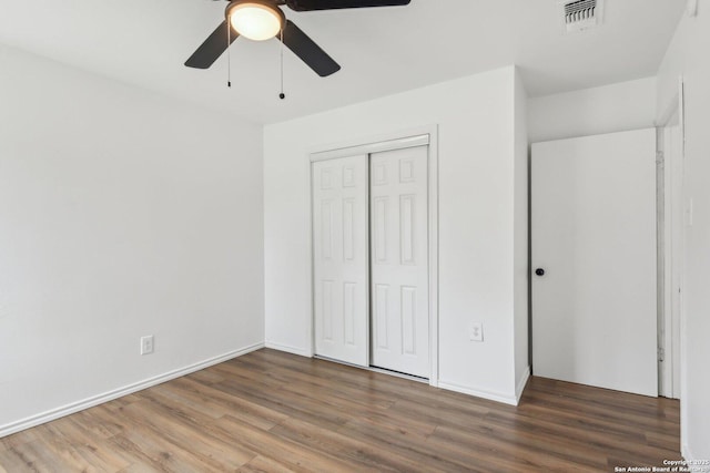 unfurnished bedroom with ceiling fan, dark hardwood / wood-style flooring, and a closet