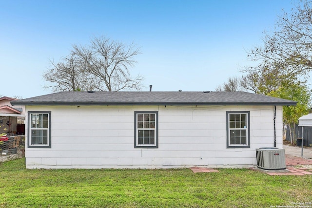 rear view of property featuring central AC unit and a yard