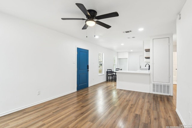 unfurnished living room featuring ceiling fan, sink, and dark hardwood / wood-style floors