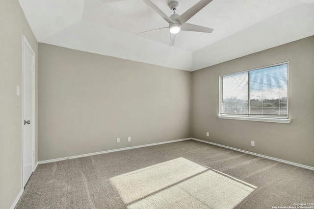 carpeted spare room featuring a raised ceiling and ceiling fan