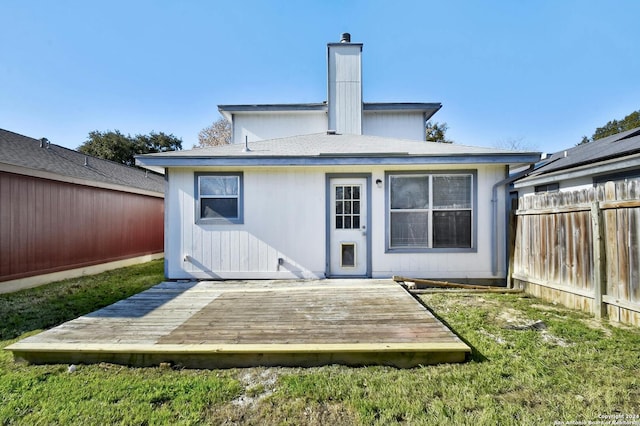 back of property featuring a wooden deck and a lawn