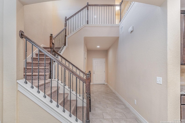 stairs with a high ceiling and tile patterned floors