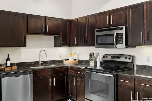 kitchen with sink, appliances with stainless steel finishes, dark brown cabinets, and dark stone countertops