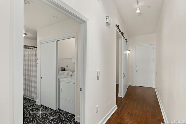 hall featuring independent washer and dryer, dark wood-type flooring, and a barn door