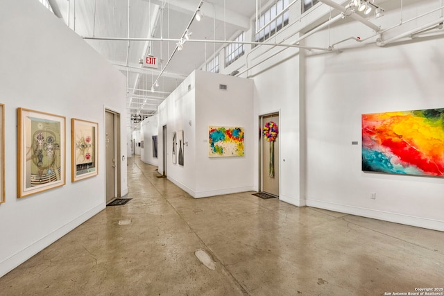 hallway featuring a towering ceiling and concrete floors