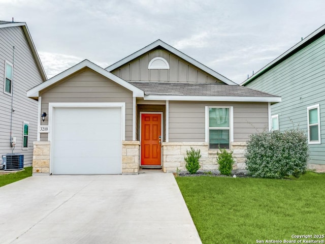 view of front of house featuring a front yard, a garage, and central air condition unit