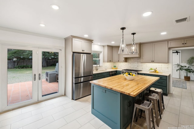 kitchen with hanging light fixtures, wooden counters, a kitchen island, stainless steel appliances, and gray cabinets