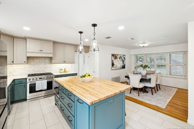 kitchen with butcher block counters, appliances with stainless steel finishes, decorative backsplash, a kitchen island, and pendant lighting