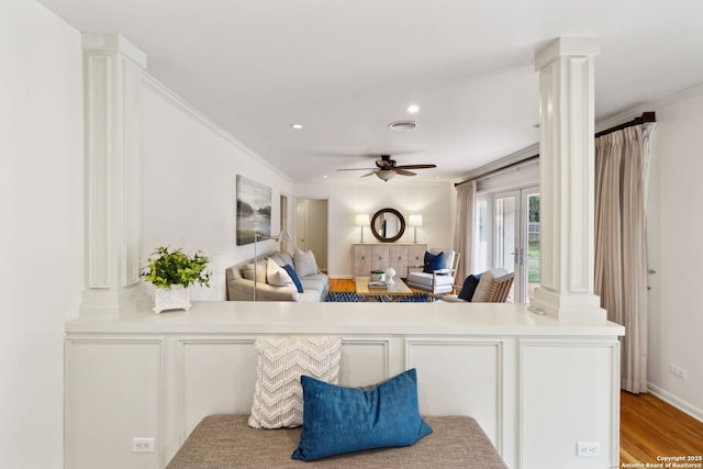 living room featuring ceiling fan, light hardwood / wood-style flooring, ornate columns, and crown molding