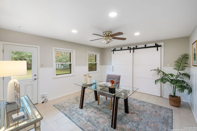 home office with ceiling fan and a barn door