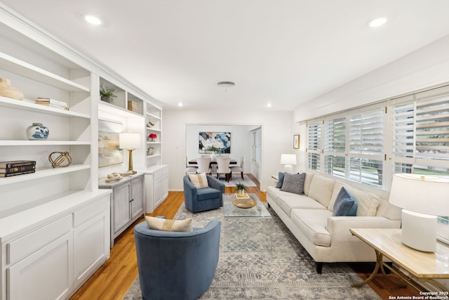 living room with light wood-type flooring and built in features