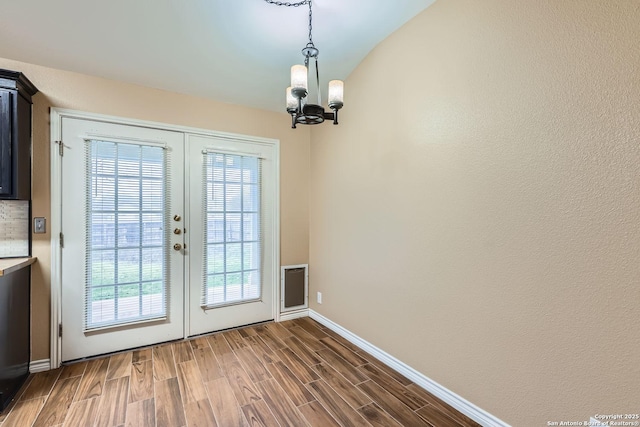 doorway to outside featuring a notable chandelier, dark hardwood / wood-style floors, and french doors