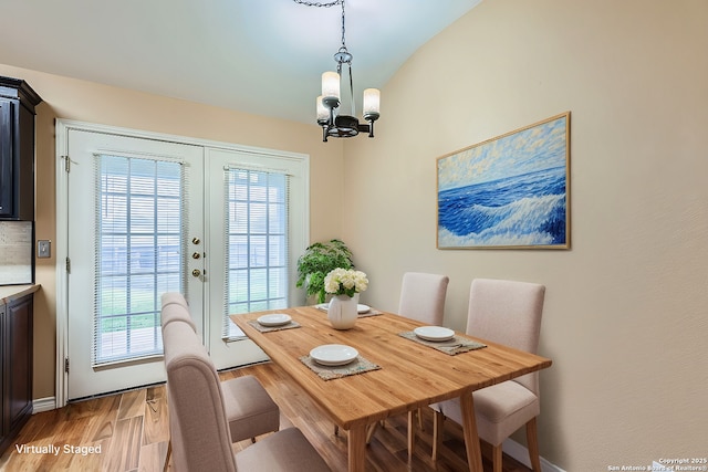 dining area featuring french doors, a notable chandelier, and light wood-type flooring