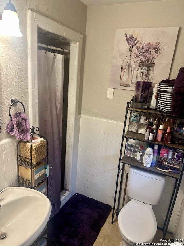 bathroom with sink, toilet, walk in shower, and tile walls