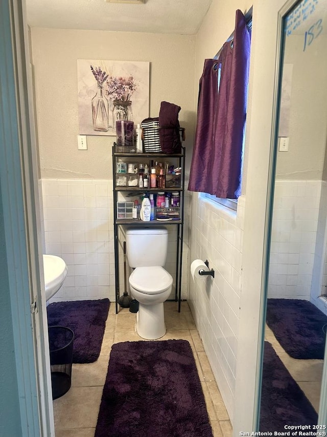 bathroom with tile walls, tile patterned flooring, and toilet