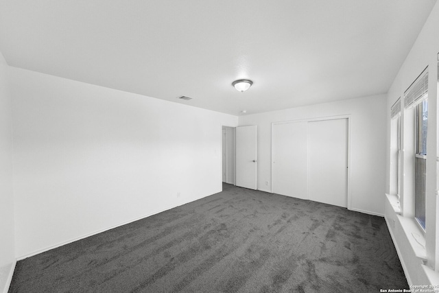 unfurnished bedroom with a closet and dark carpet