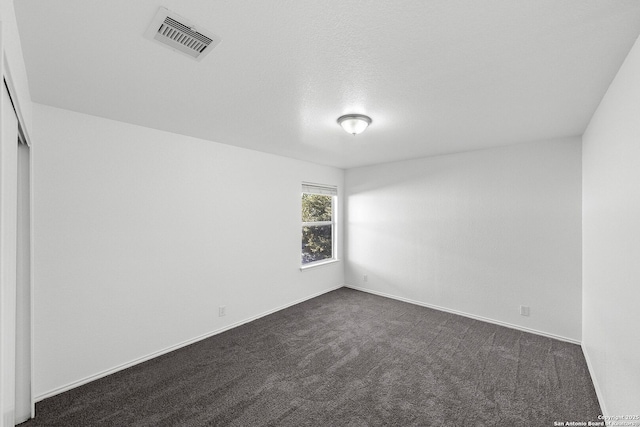 spare room with dark carpet