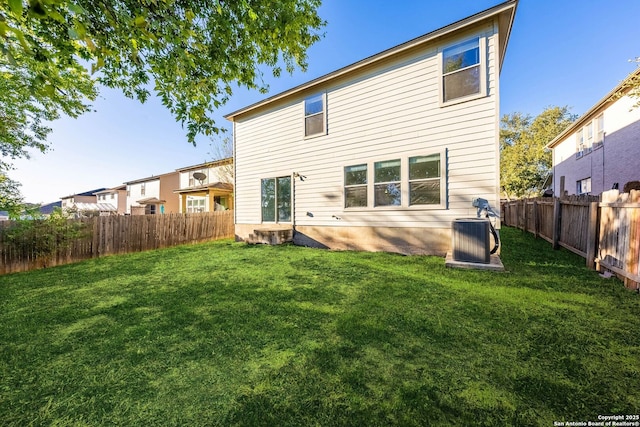 rear view of property featuring a yard and central AC unit