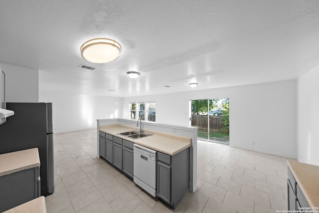 kitchen with a center island with sink, stainless steel fridge, gray cabinets, white dishwasher, and sink