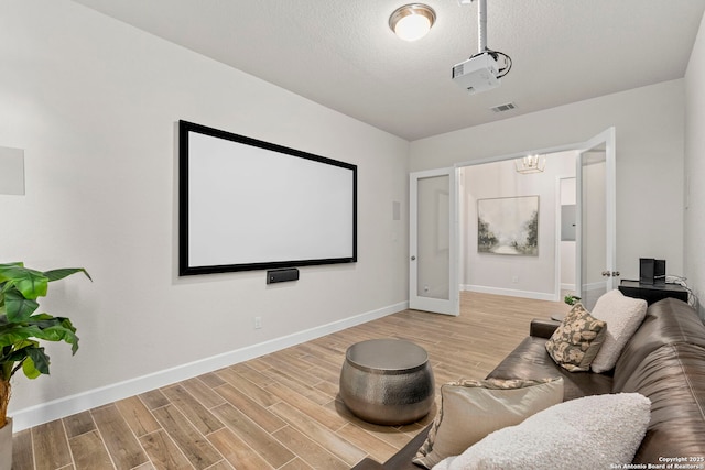 home theater with light wood-type flooring and a textured ceiling