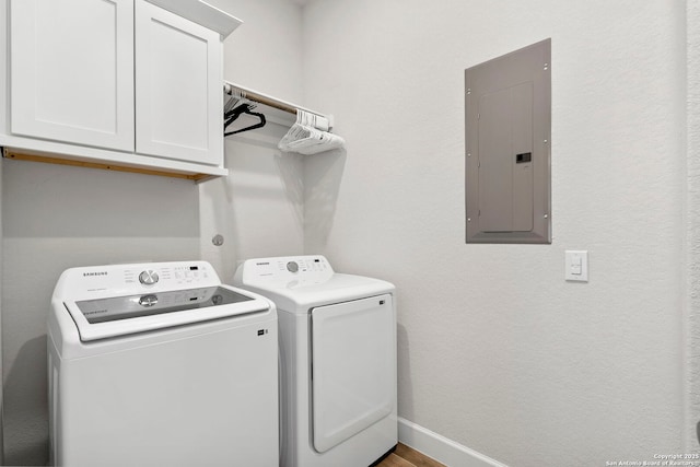 clothes washing area featuring electric panel, cabinets, and washing machine and clothes dryer