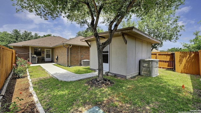 rear view of house with central air condition unit, a patio area, and a lawn