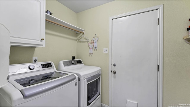 clothes washing area with separate washer and dryer and cabinets