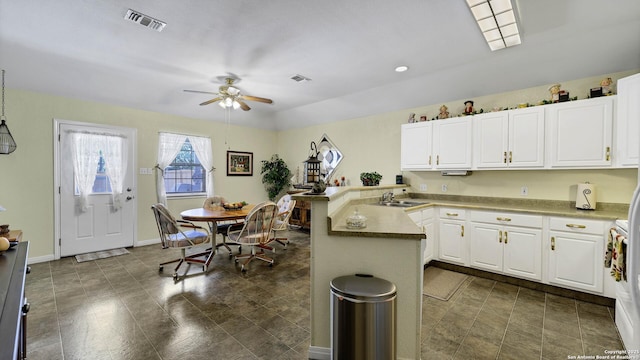 kitchen with ceiling fan, white cabinetry, sink, and kitchen peninsula