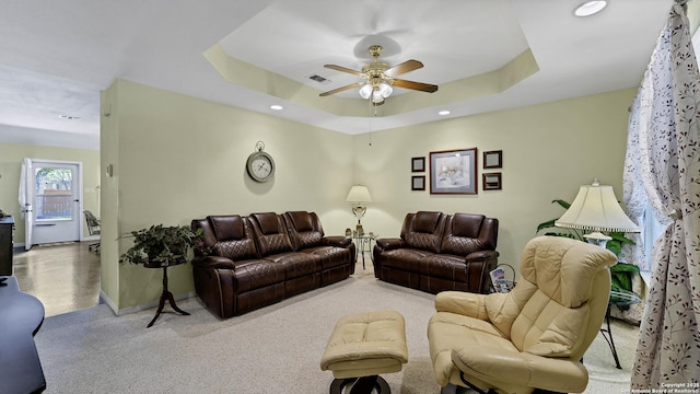 carpeted living room featuring a raised ceiling and ceiling fan