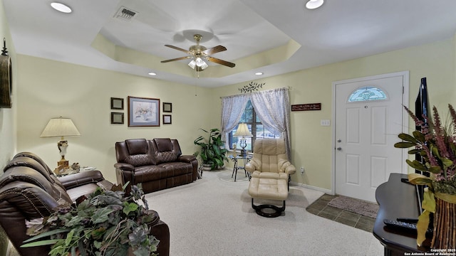 living room with carpet floors, ceiling fan, and a tray ceiling