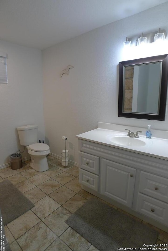 bathroom with toilet, vanity, and tile patterned floors