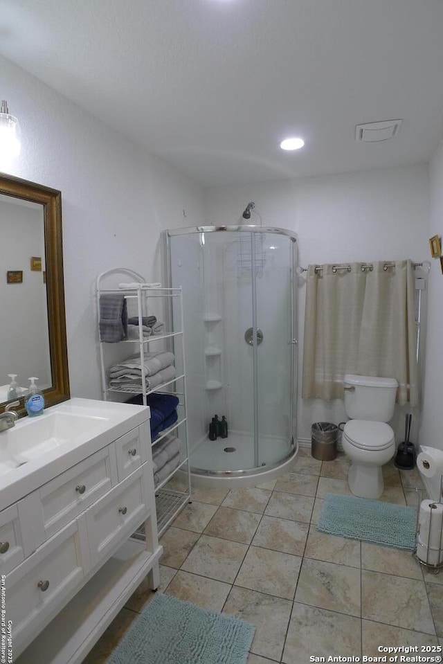 bathroom with a shower with shower door, vanity, tile patterned flooring, and toilet