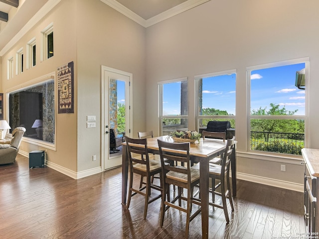 dining area with a towering ceiling, dark wood-type flooring, and crown molding