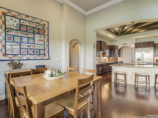 dining space featuring beam ceiling, crown molding, dark hardwood / wood-style floors, and a high ceiling