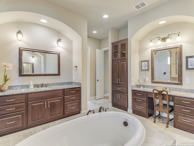 bathroom with tiled tub and vanity