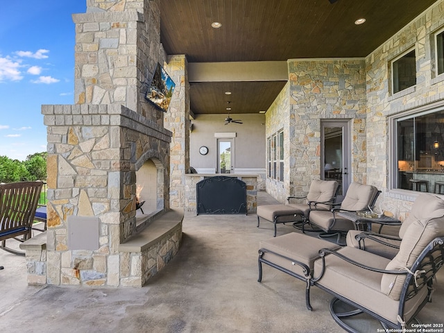 view of patio with ceiling fan and an outdoor stone fireplace