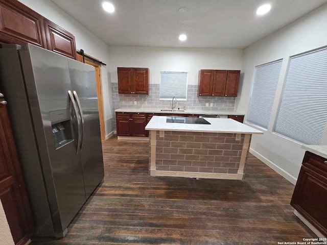 kitchen featuring dark wood-type flooring, a center island, stainless steel refrigerator with ice dispenser, a barn door, and sink