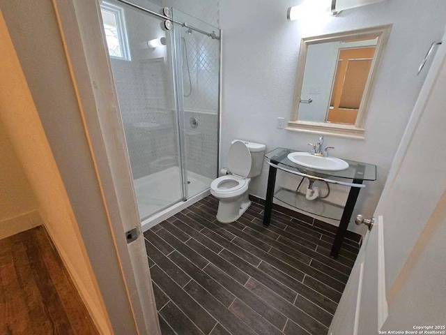 bathroom with sink, an enclosed shower, and toilet